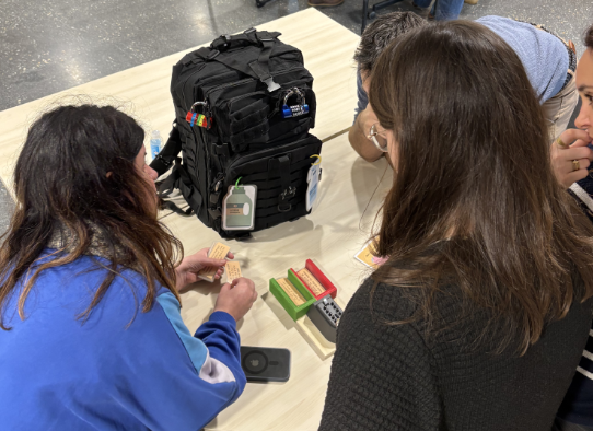 Plusieurs personnes sont autour d'un sac à dos dont les poches sont fermées par des cadenas