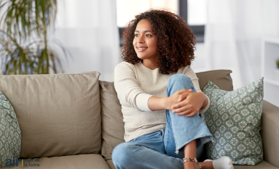 Une femme est assise sur un canapé et sourit